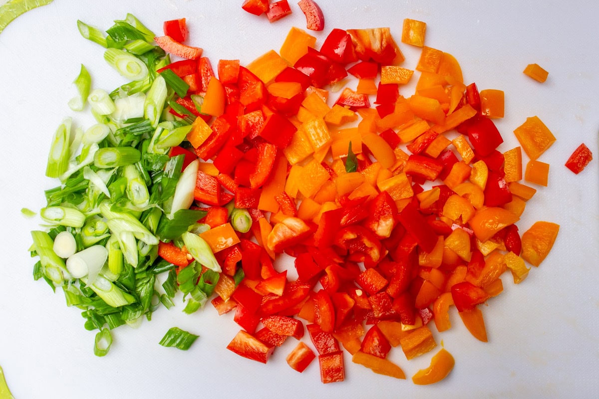 Chopped peppers and green onions on cutting board.
