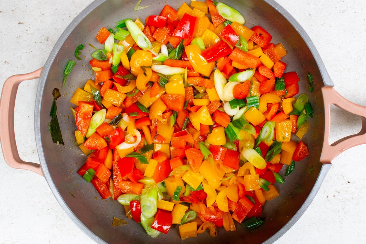 Peppers and onions sauteing in pan.
