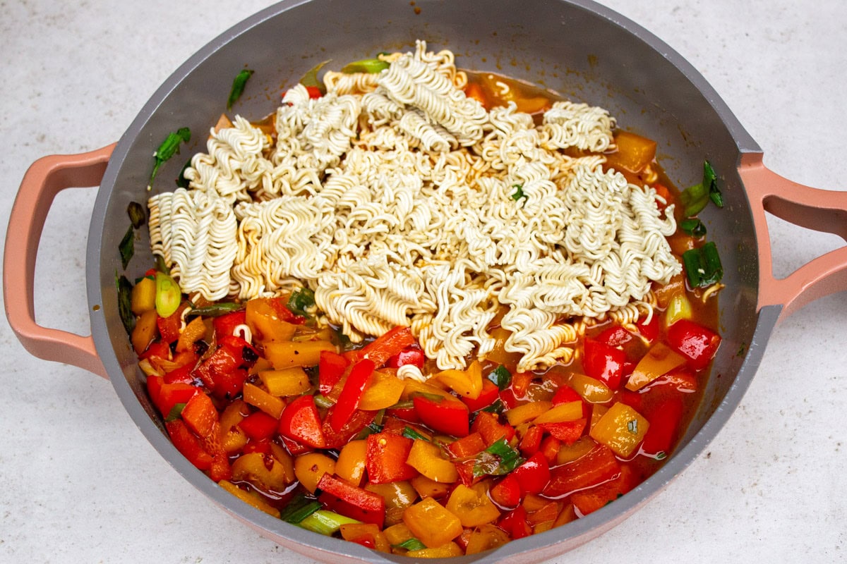 Ramen noodles in half of pan with veggies on other half of pan.