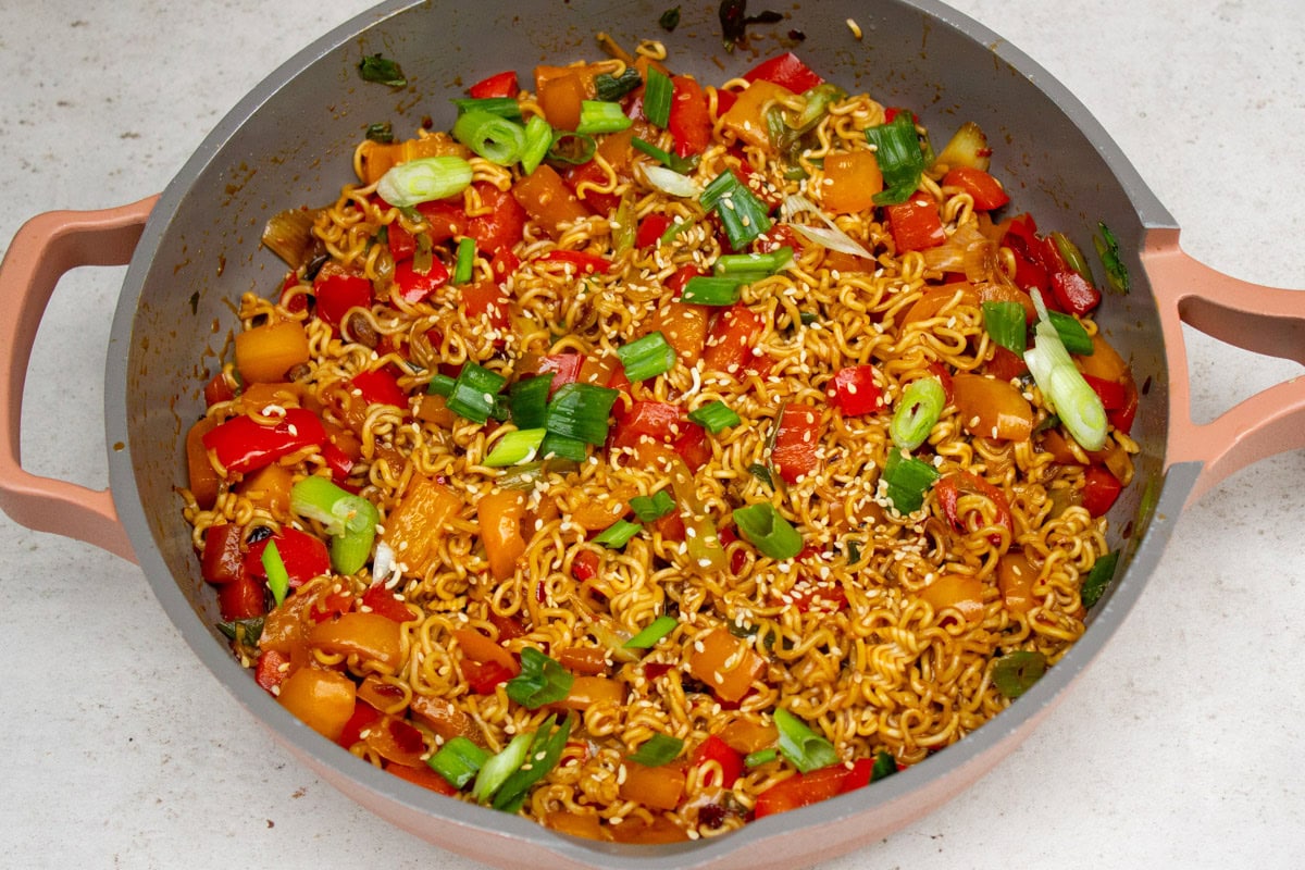 Spicy ramen noodles in pan garnished with green onions.