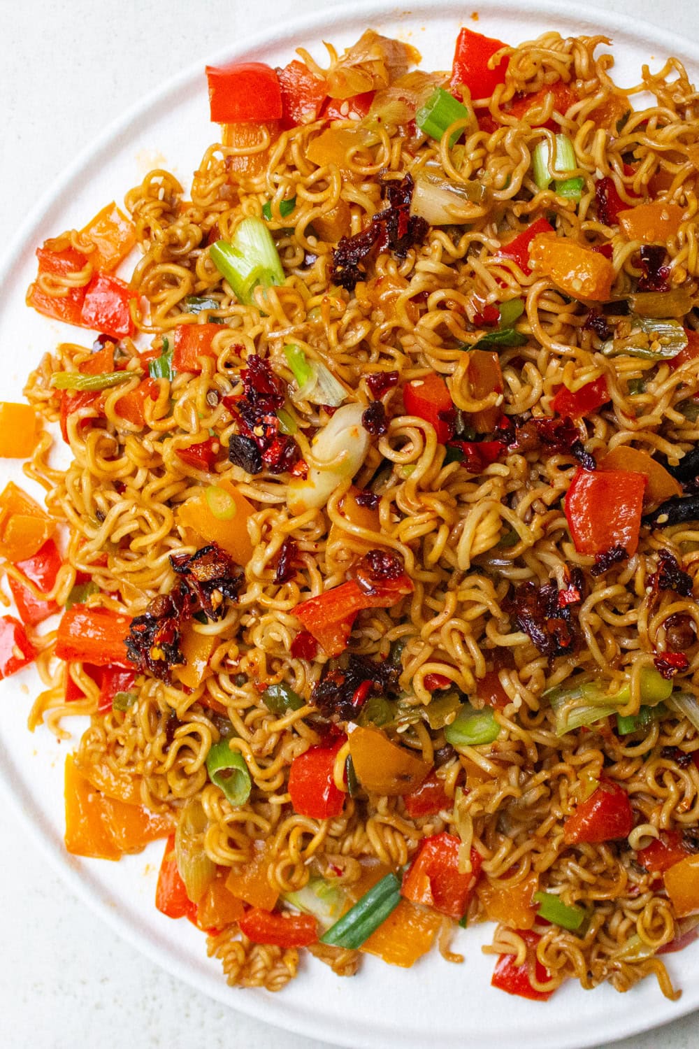 Spicy ramen noodles with veggies on plate with chop sticks.
