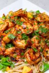 BBQ shrimp over noodles with snap peas and peaches.