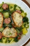 Bowl of soup with kale, potato chunks and sausage disks.