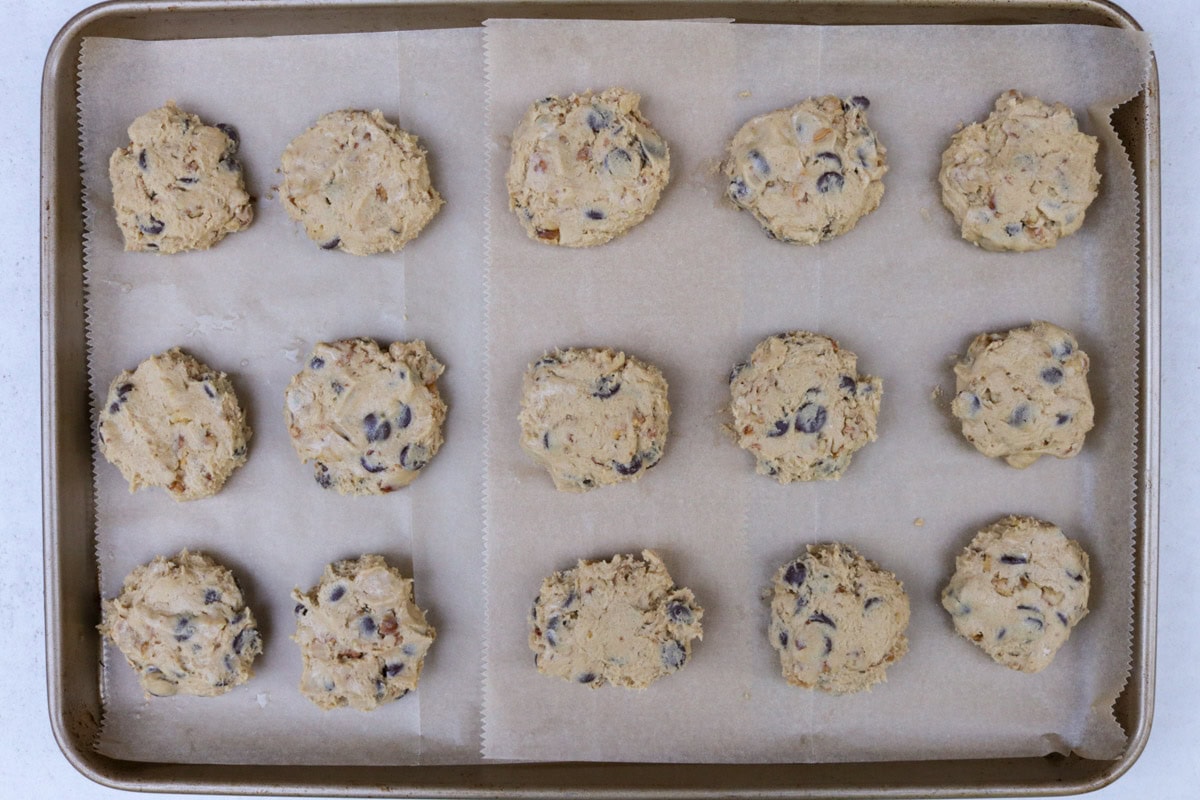 Cookie dough balls, slightly flattened on parchment lined baking sheet.