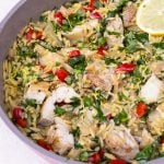Lemon chicken and orzo with veggies, herbs and lemon zest in skillet.