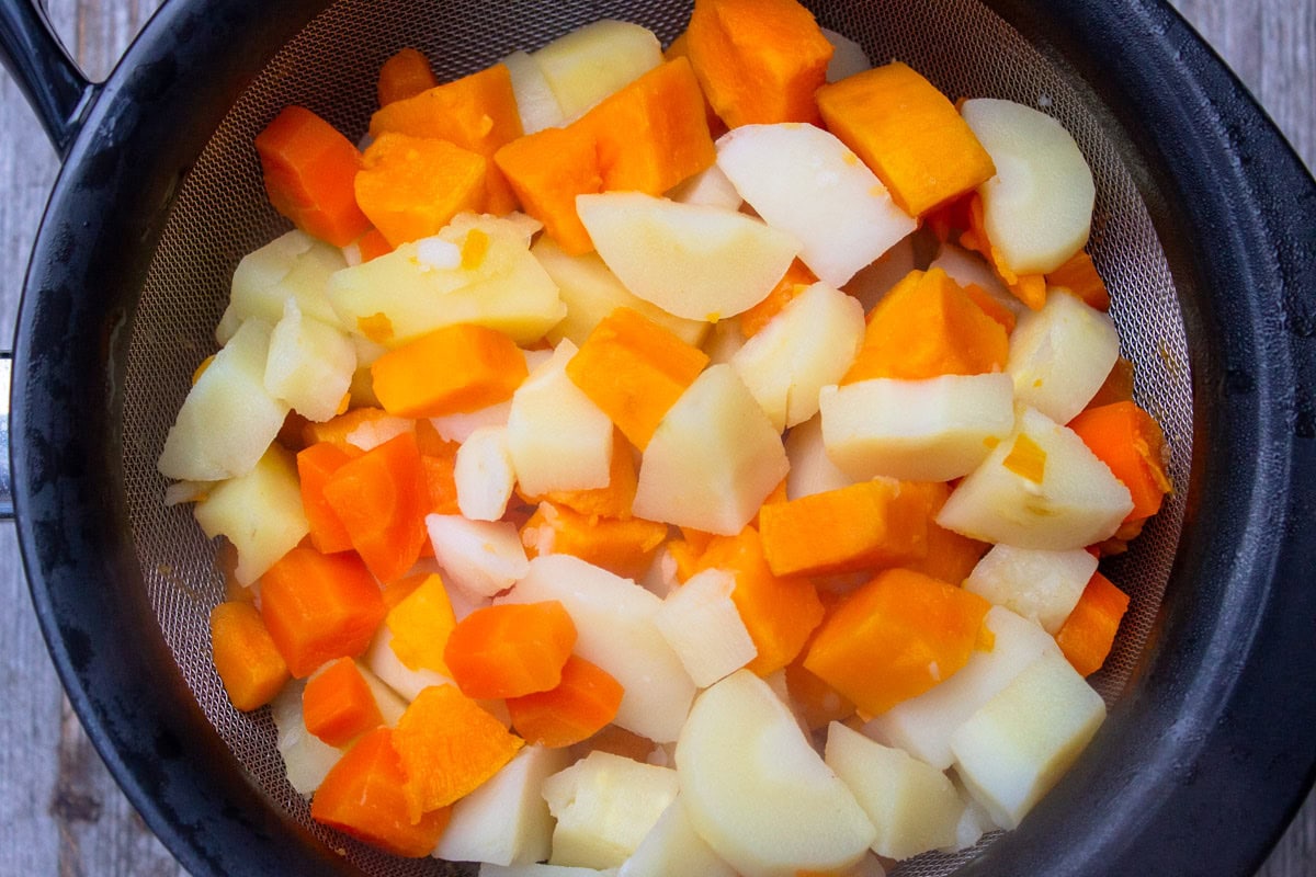 Boiled root vegetables in strainer. 