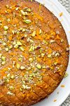 Garnished orange polenta cake on white plate.