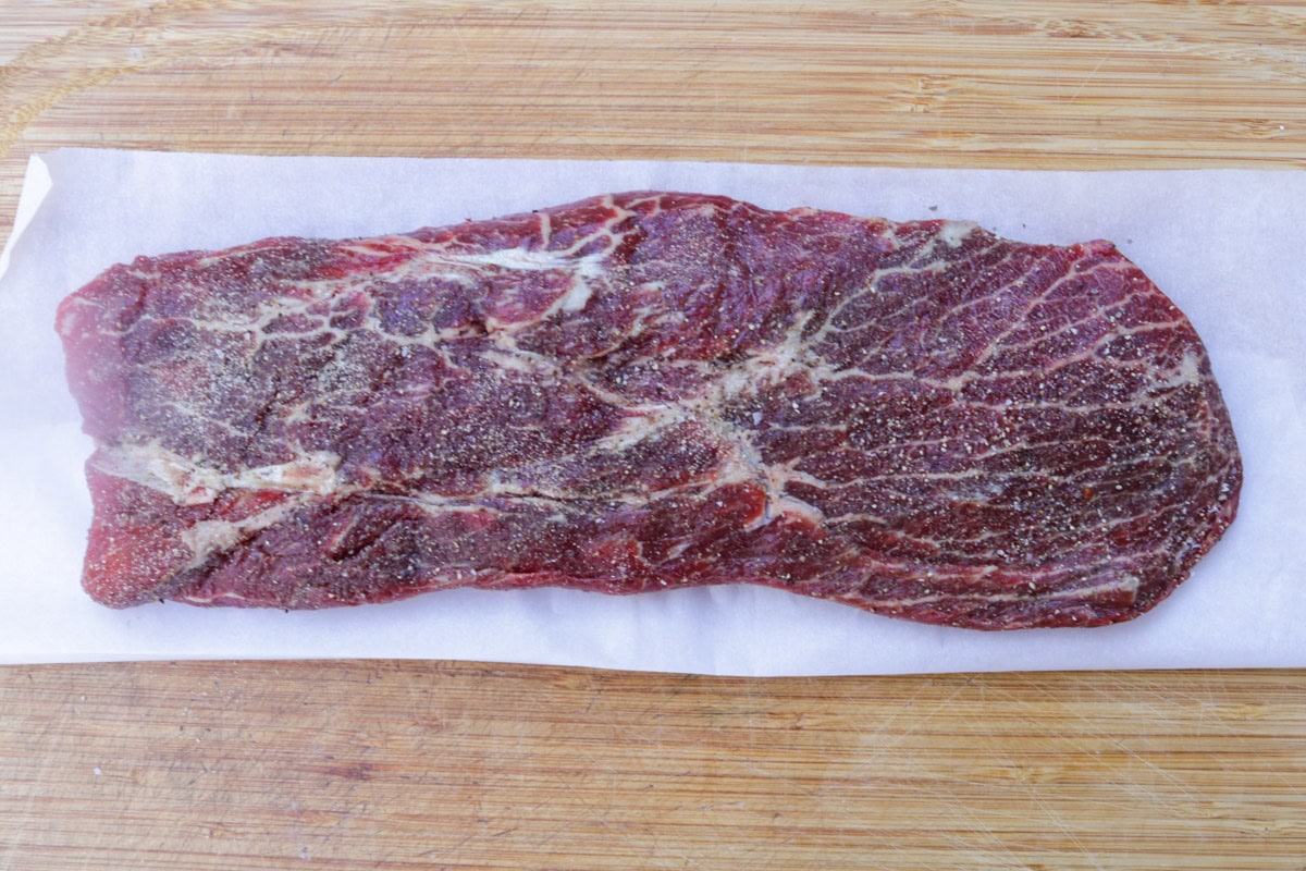 Seasoned flat iron steak on cutting board.