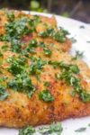 Four crispy Italian chicken cutlets on a plate.