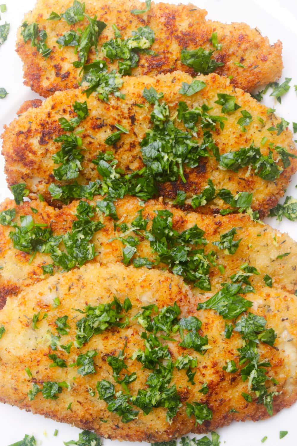 Four crispy Italian chicken cutlets on a plate.