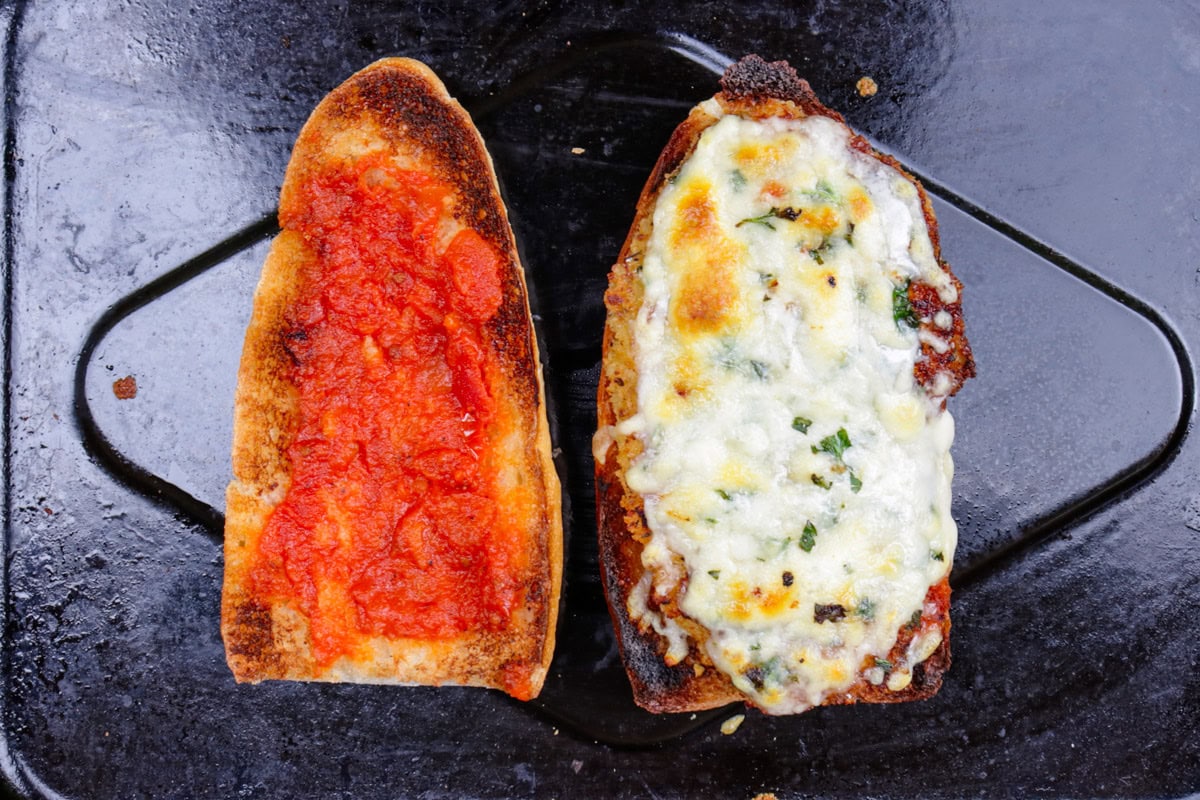 Half roll with tomato sauce, chicken and melted cheese beside other half of roll with tomato sauce.