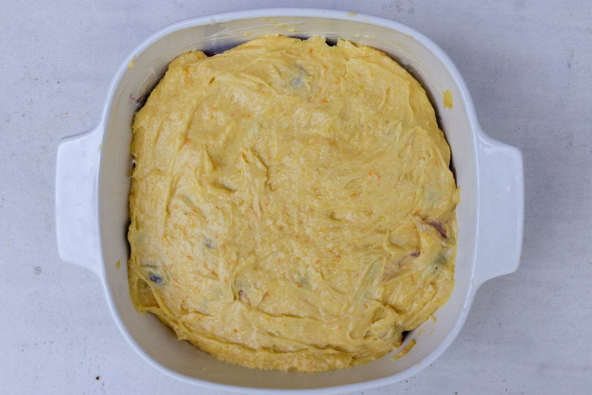 Berries topped with cake batter in baking dish.