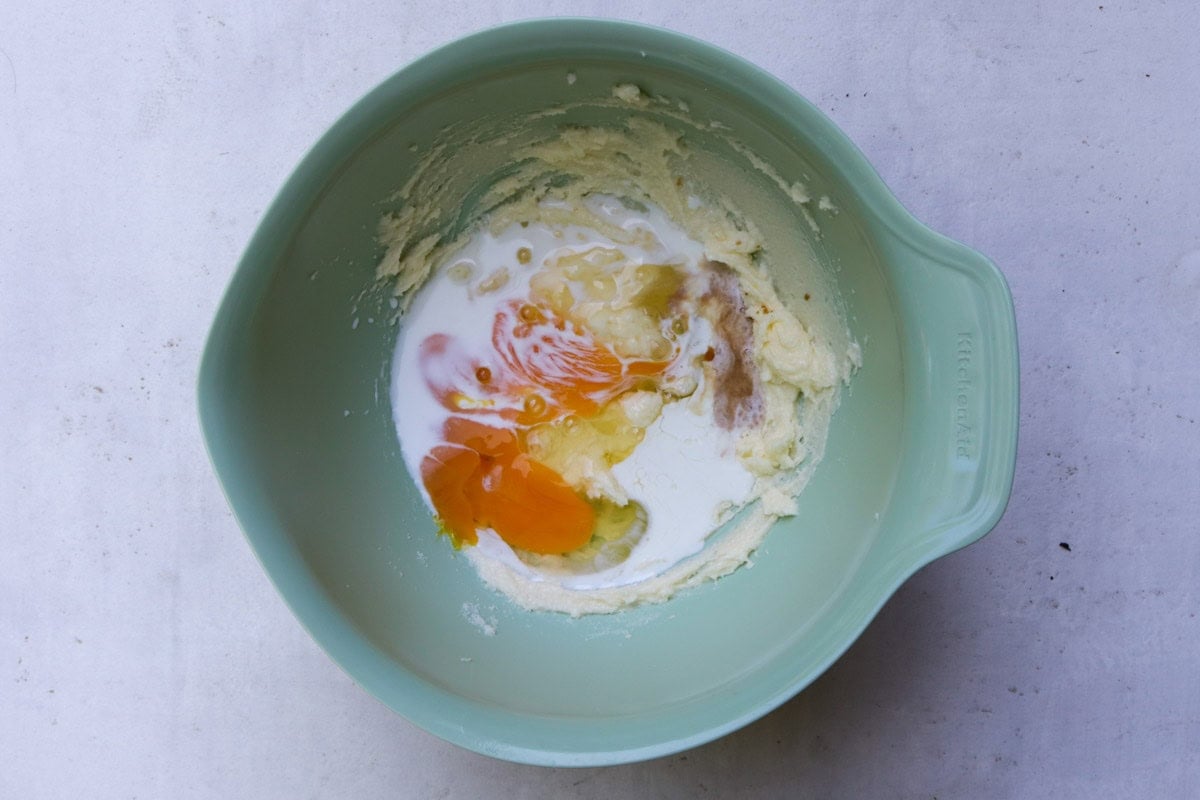Butter, sugar, eggs, vanilla in mixing bowl.