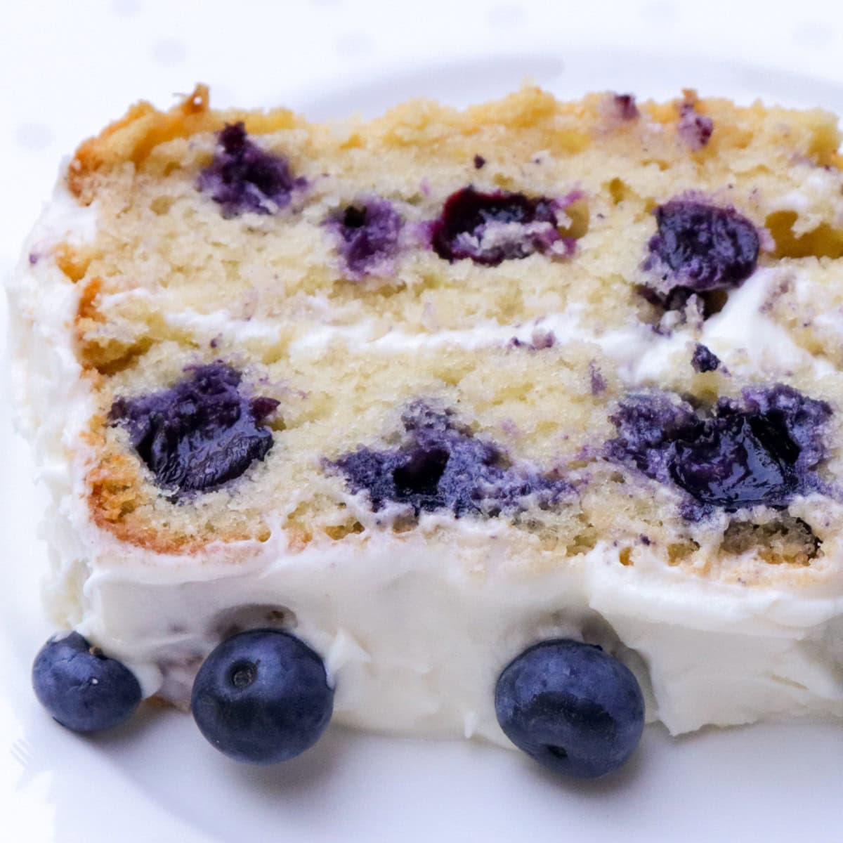 Piece of blueberry cake with cream cheese frosting.
