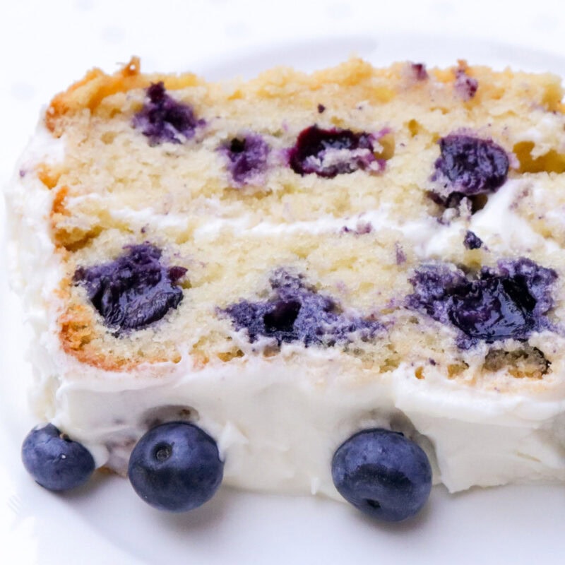 Piece of blueberry cake with cream cheese frosting.