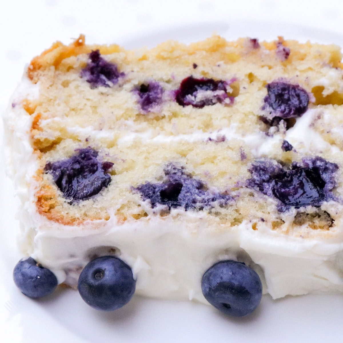 Piece of blueberry cake with cream cheese frosting.