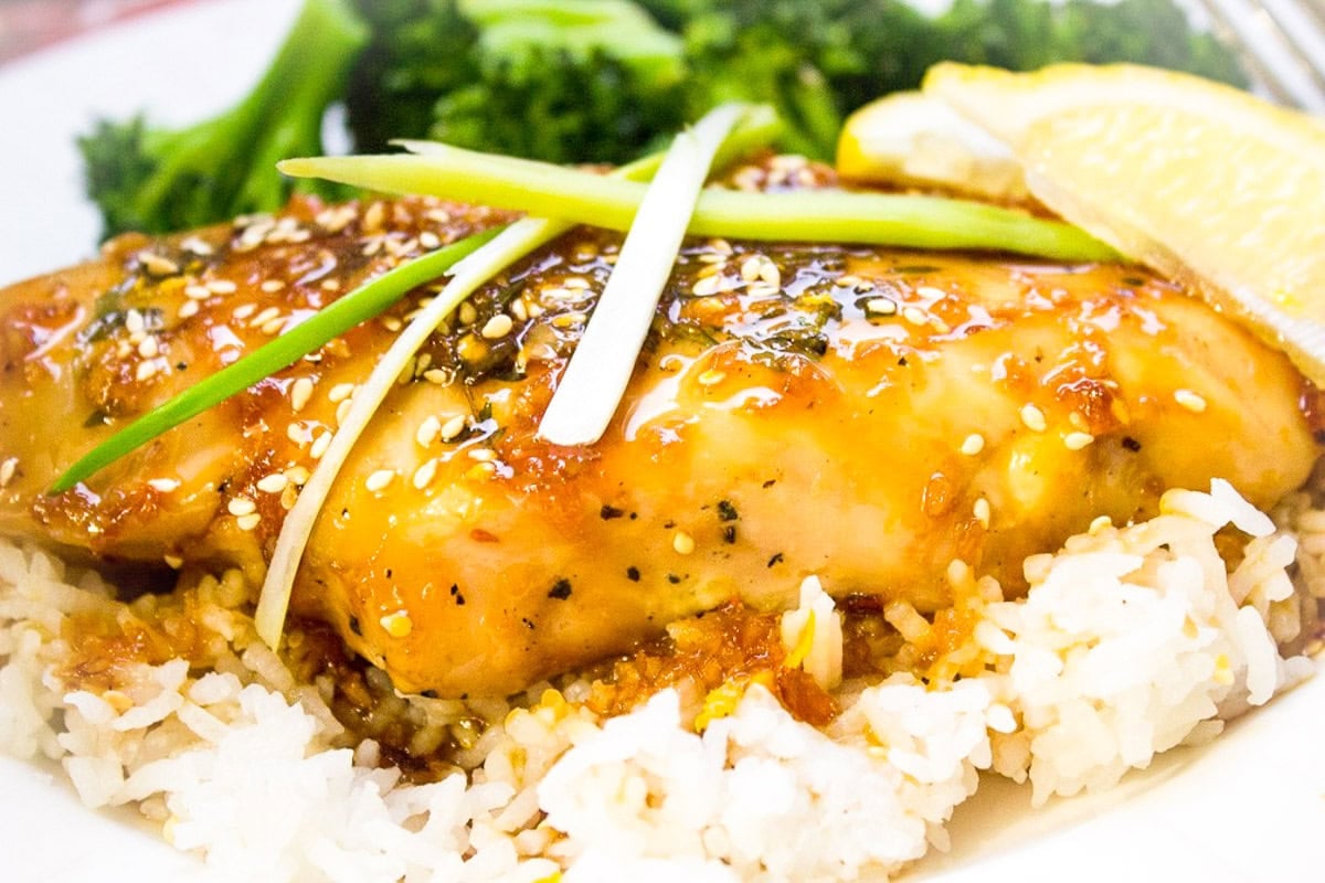 Glazed chicken breast over rice topped with sesame seeds and green onions.