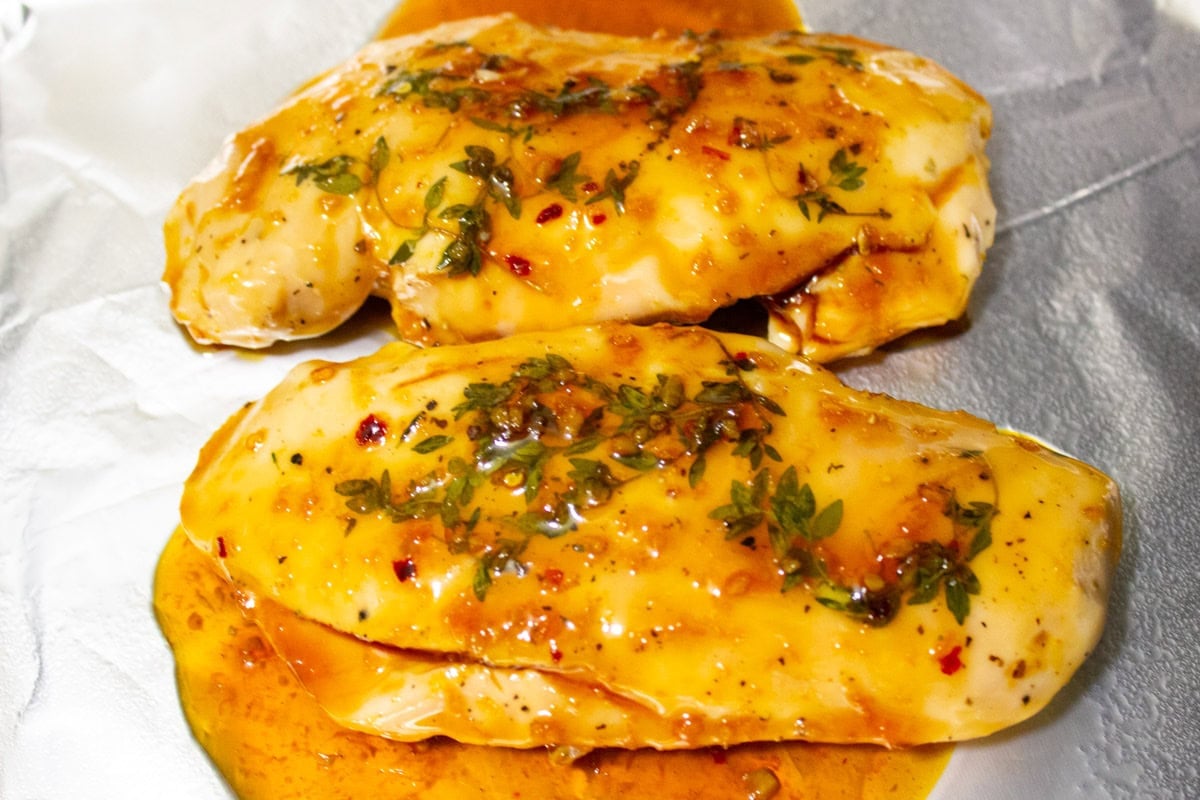 Sous vide chicken on pan topped with citrus glaze.