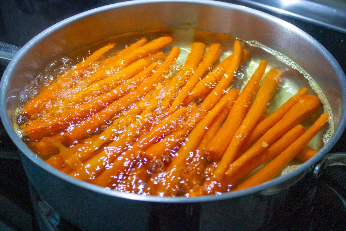 Carrots parboiling in large pan on stovetop.