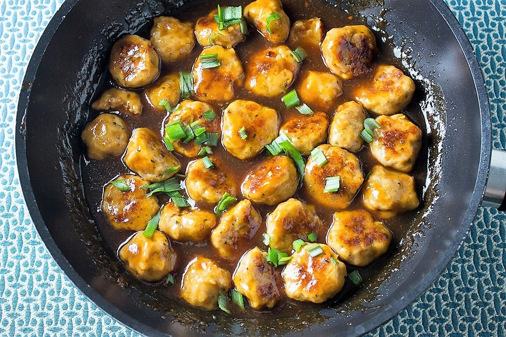 ChiCken meatballs in a sauce in skillet. 