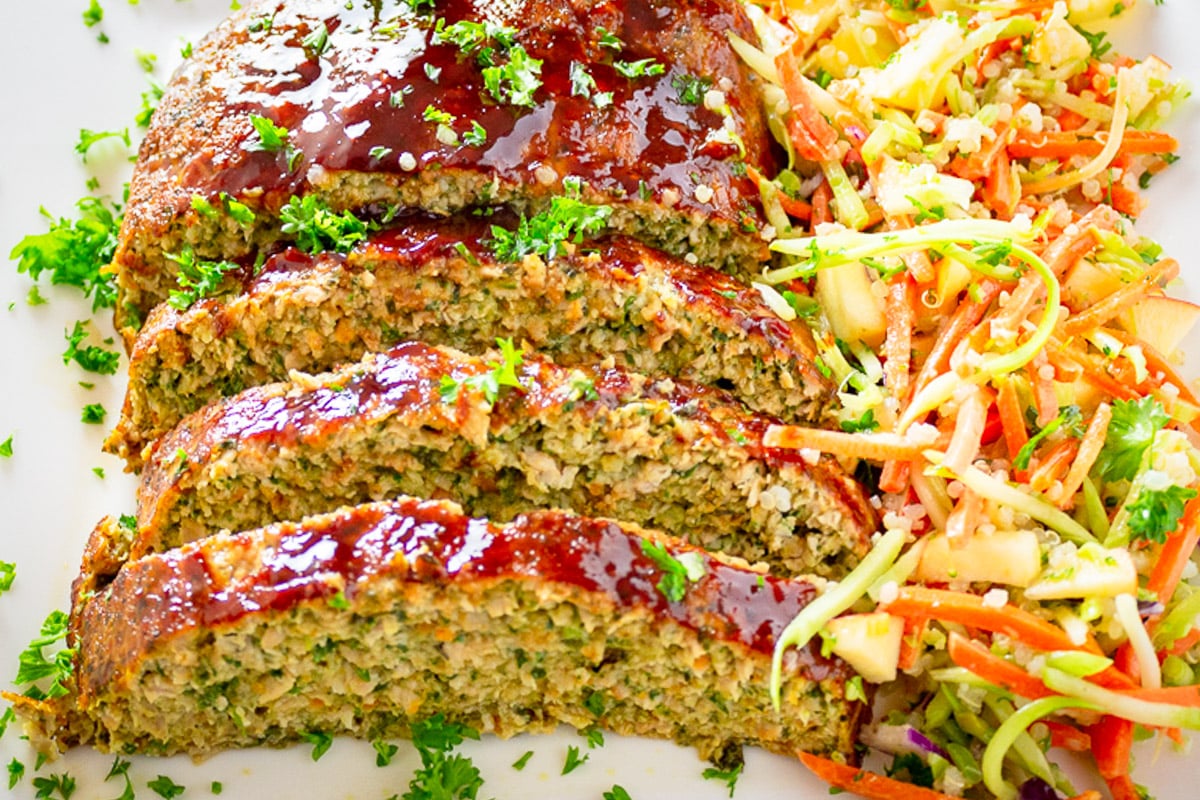 Sliced glazed chicken meatloaf with coleslaw on a plate.