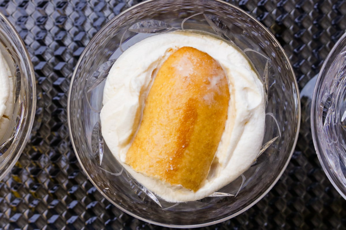 Cream and ladyfingers layered in a glass dessert cup.