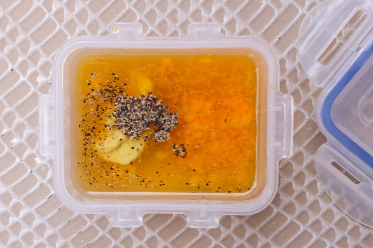Unmixed mandarin orange vinaigrette ingredients in a small plastic container.