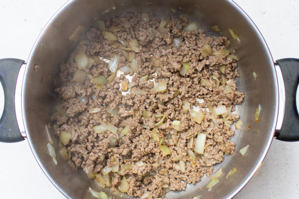 Ground beef and onions cooked in pot.