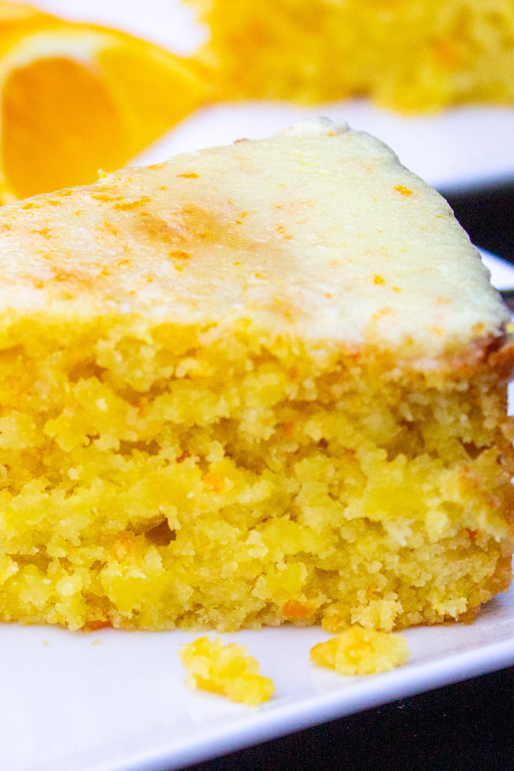 Slice of glazed orange cake on white plate.