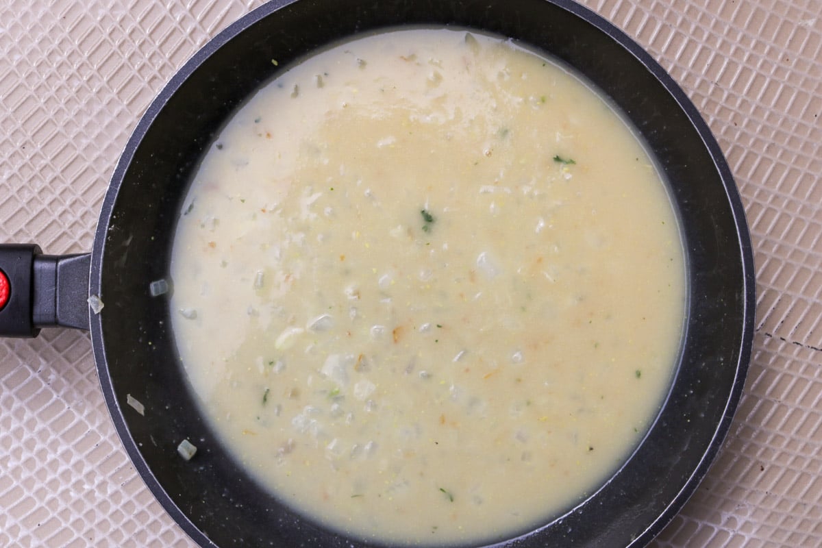 Thickened chicken sauce with onions in a skillet.