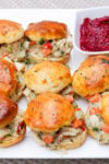 Chicken pot pie filling in biscuit sliders on a plate with cranberry relish on the side.