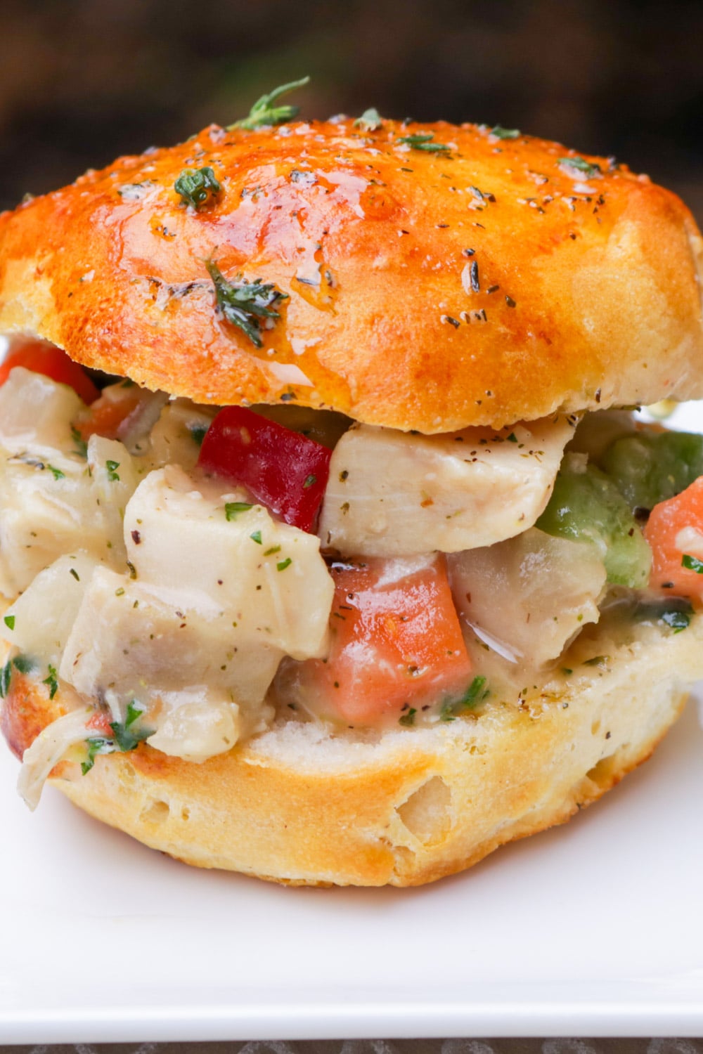 Slider biscuit filled with chicken pot pie filling on a plate.