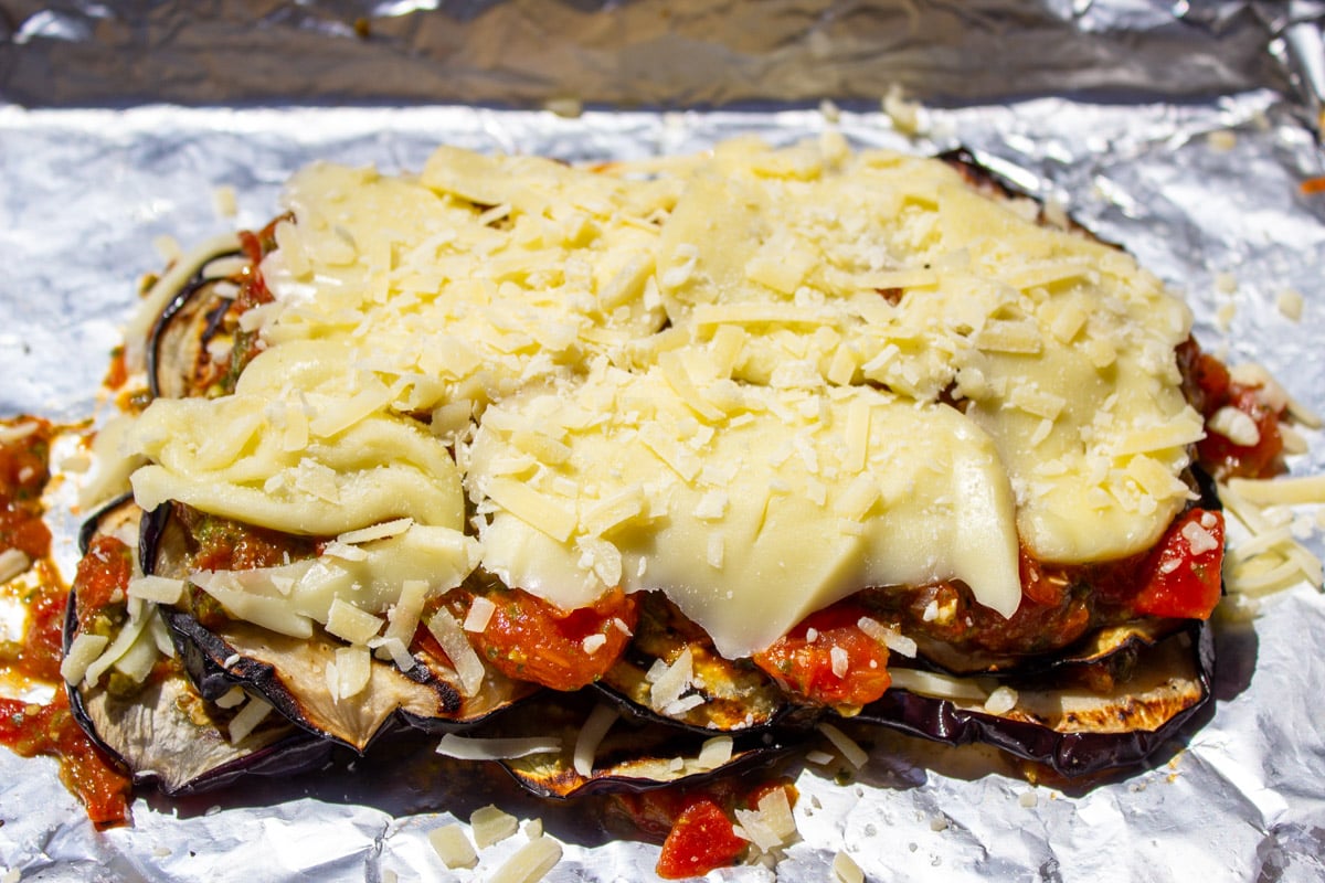 Layered eggplant parmesan on foil lined skillet before baking.