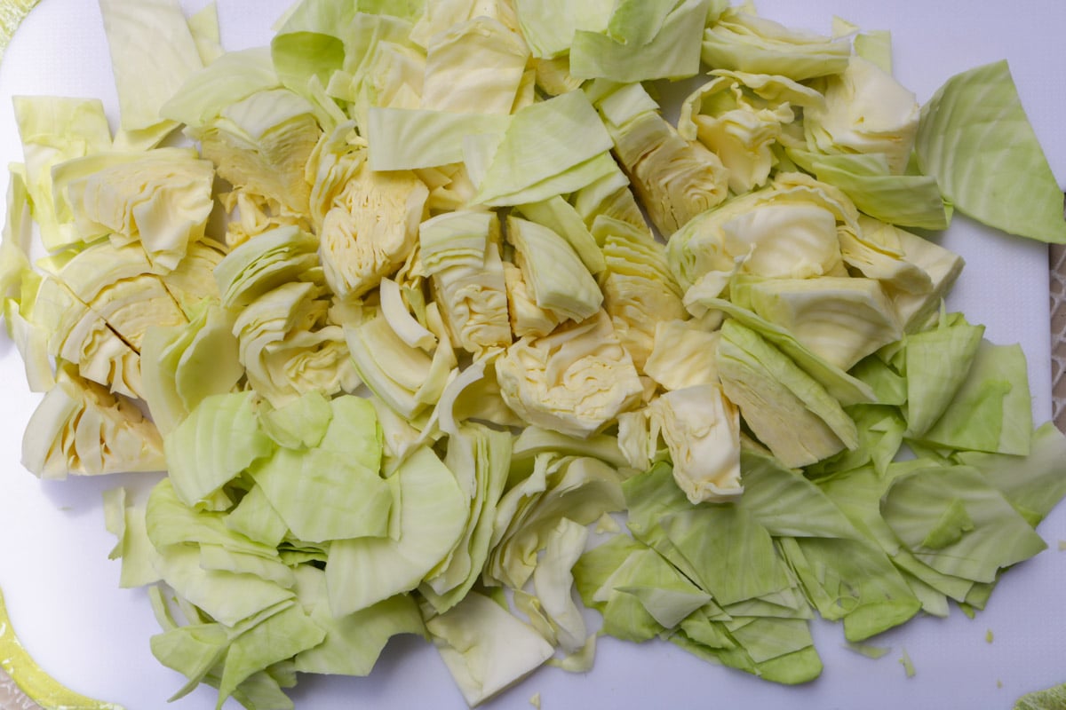 Cabbage cut into chunks on cutting board.