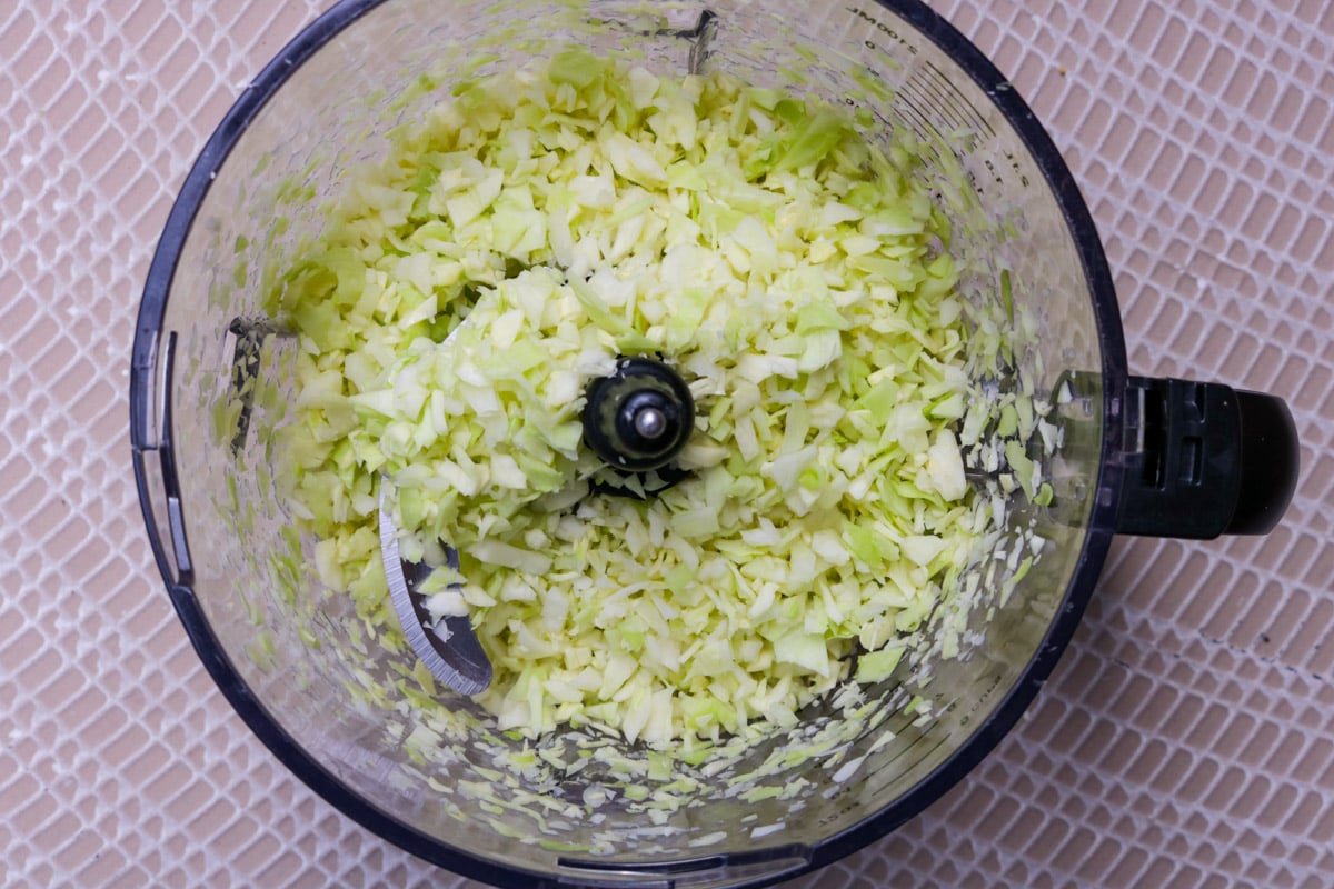 Chopped cabbage in food processor bowl.