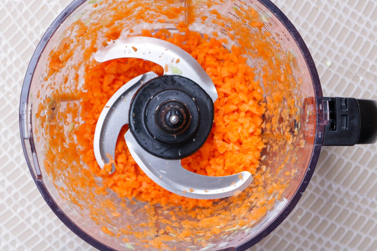 Finely chopped carrot in food processor bowl.