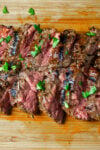 Sliced flank steak on wooden cutting board.