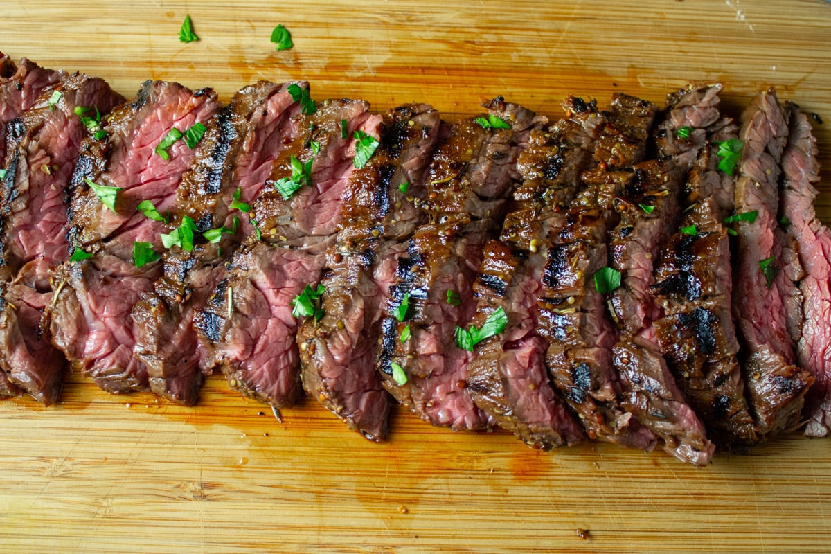 Sliced flank steak on wooden cutting board.