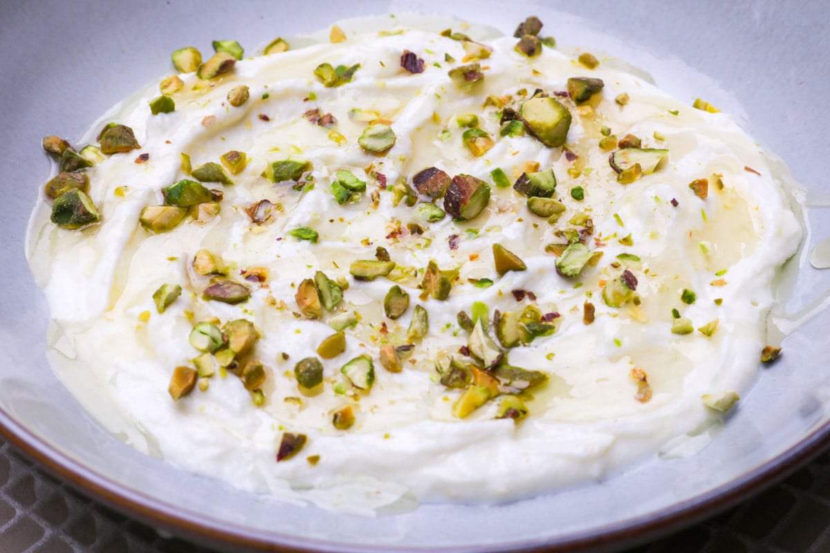 Whipped ricotta in a bowl topped with honey, olive oil and chopped pistachios.