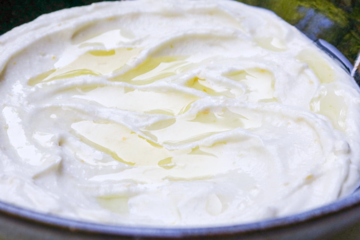Fluffy whipped ricotta in a shallow bowl, drizzled with olive oil.