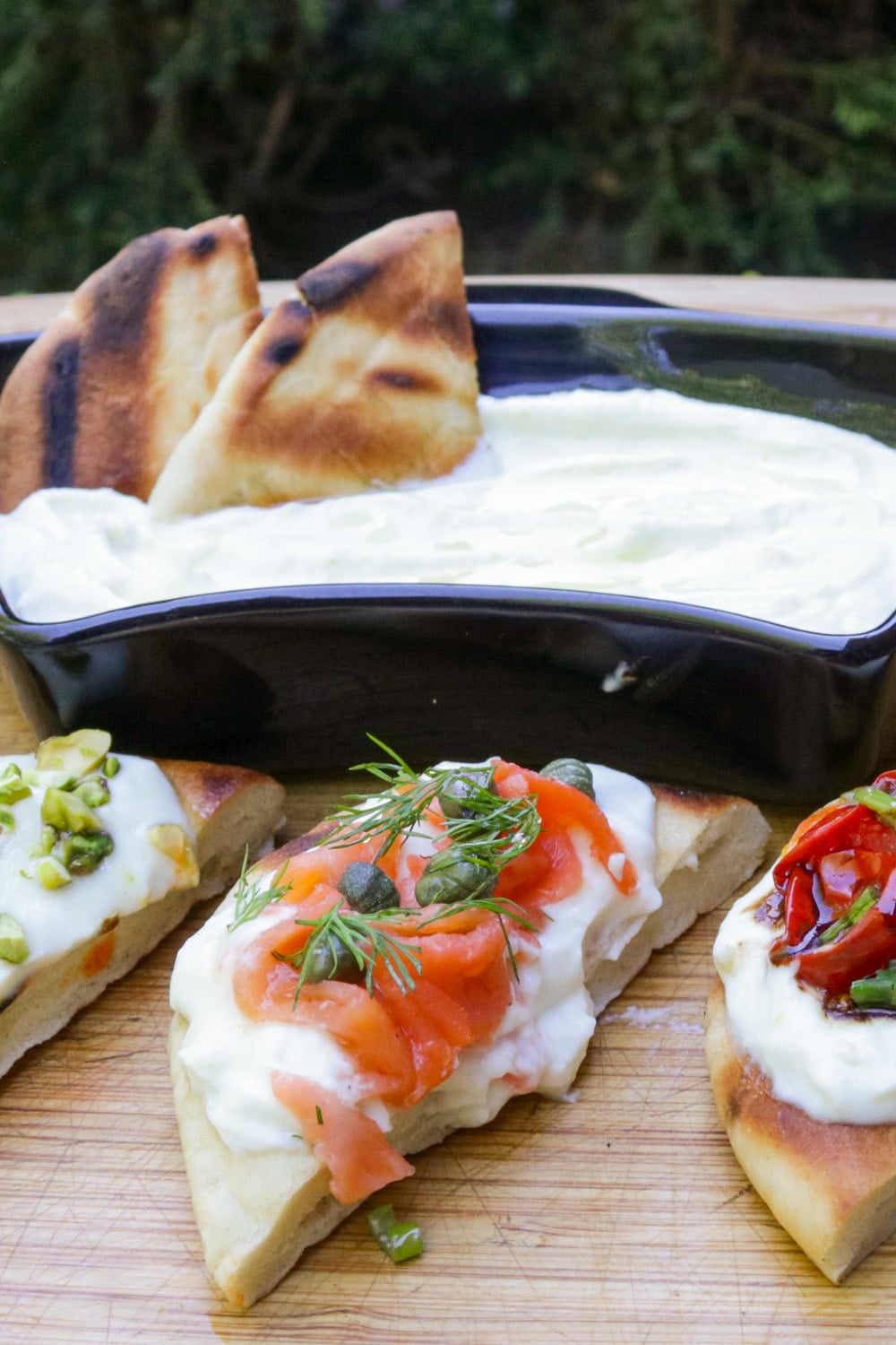 Bowl of whipped ricotta with bite size appetizers with different toppings - tomato, smoked salmon and chili crisp honey.