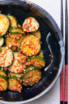 Bowl of Korean cucumber salad with chopsticks beside it.