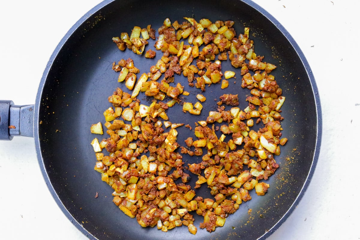 Onion, ginger, garlic, curry powder and tomato paste mixed together in skillet.