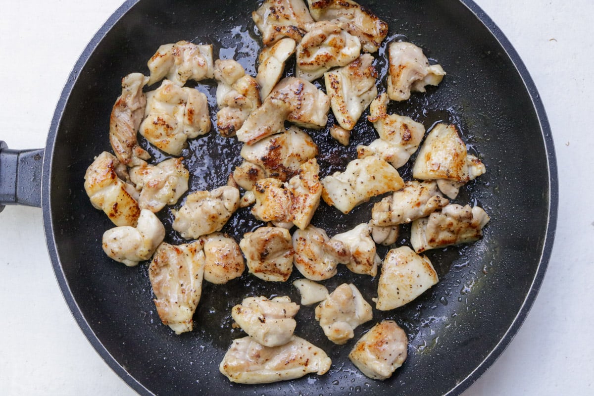 Stir fried pieces of chicken in skillet.