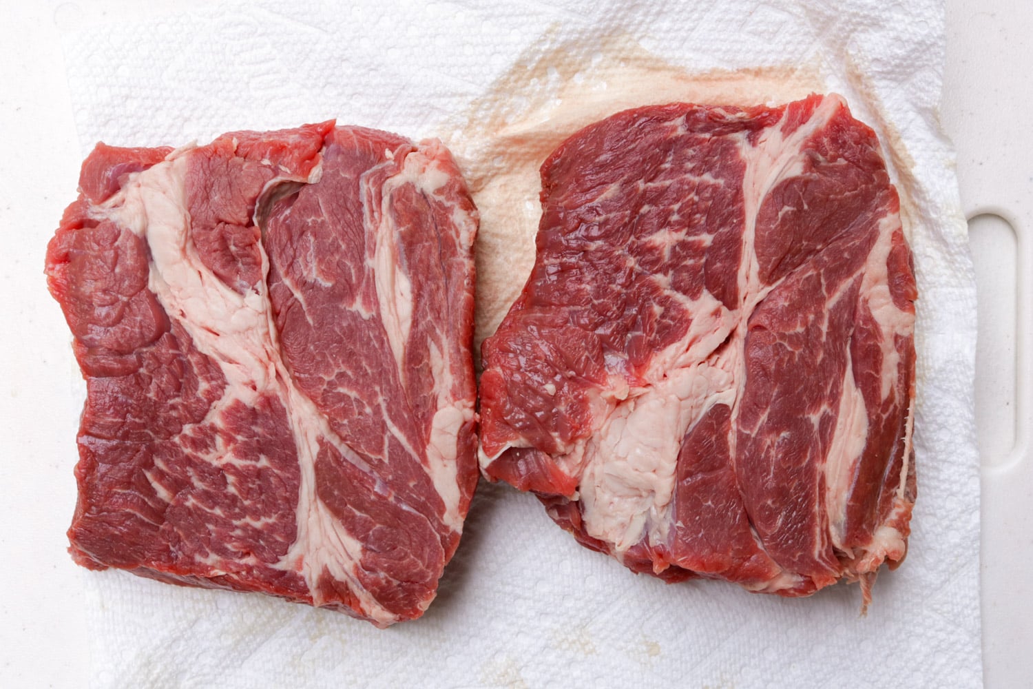 Chuck roast cut in half horizontally on cutting board.