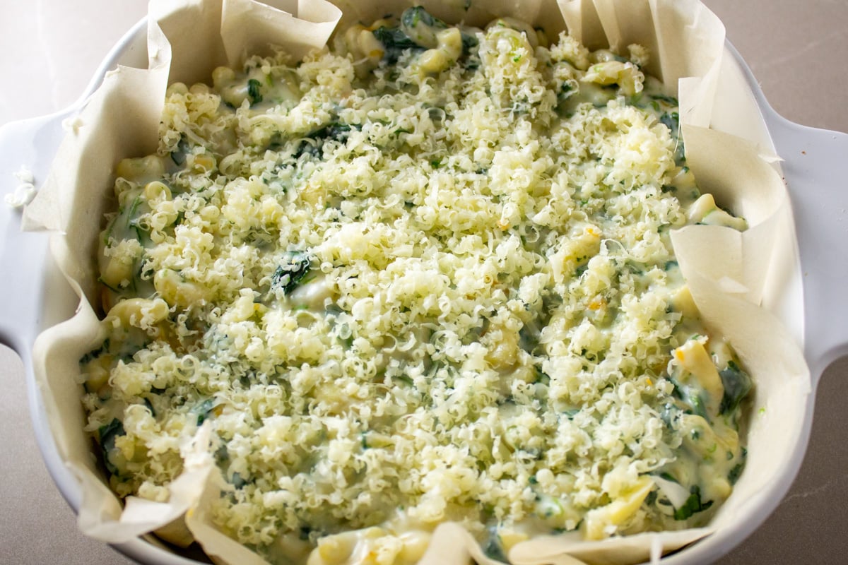 Spinach mac and cheese in casserole dish lined with parchment paper.