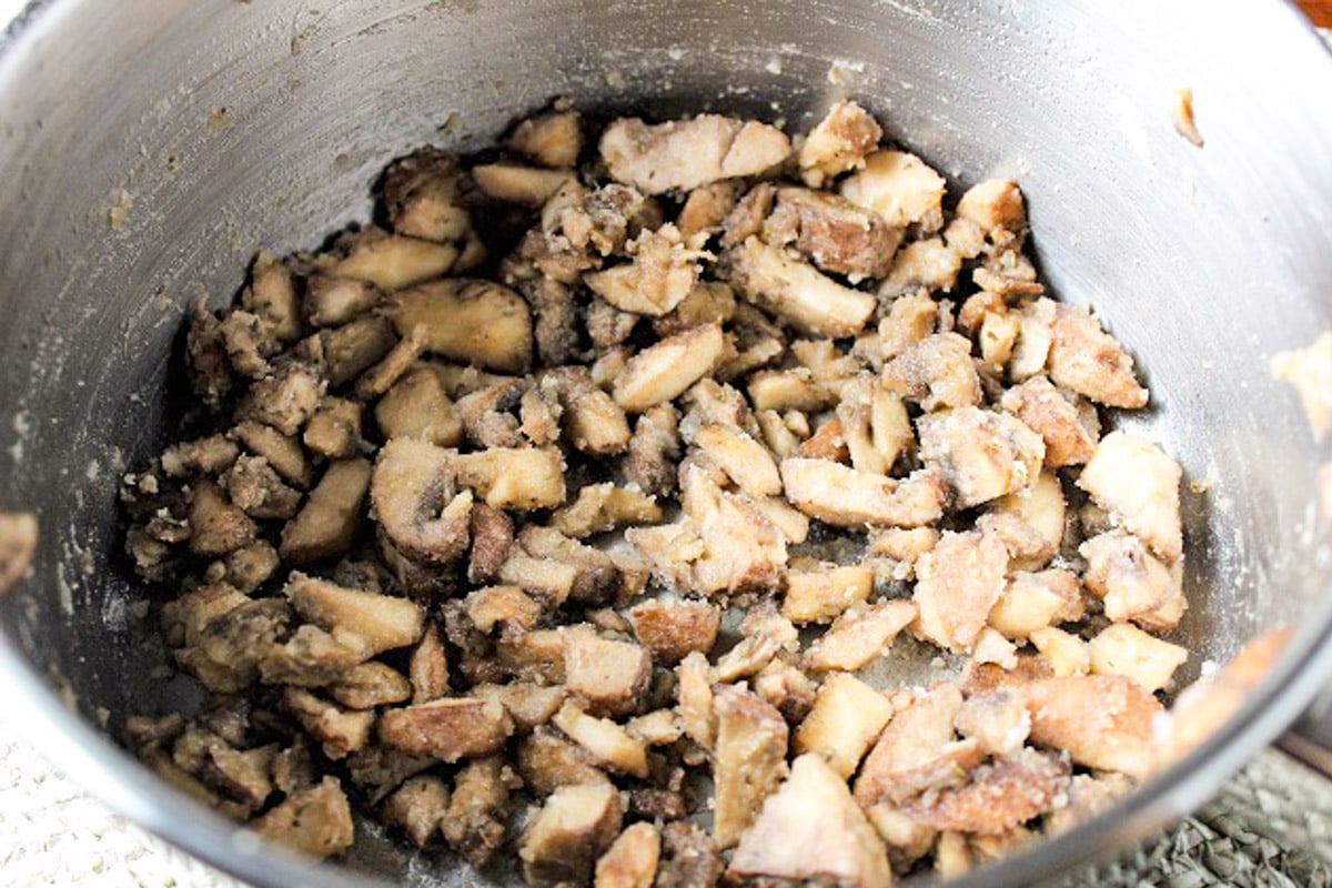 Sauteed mushrooms with flour for thickening in a pot.