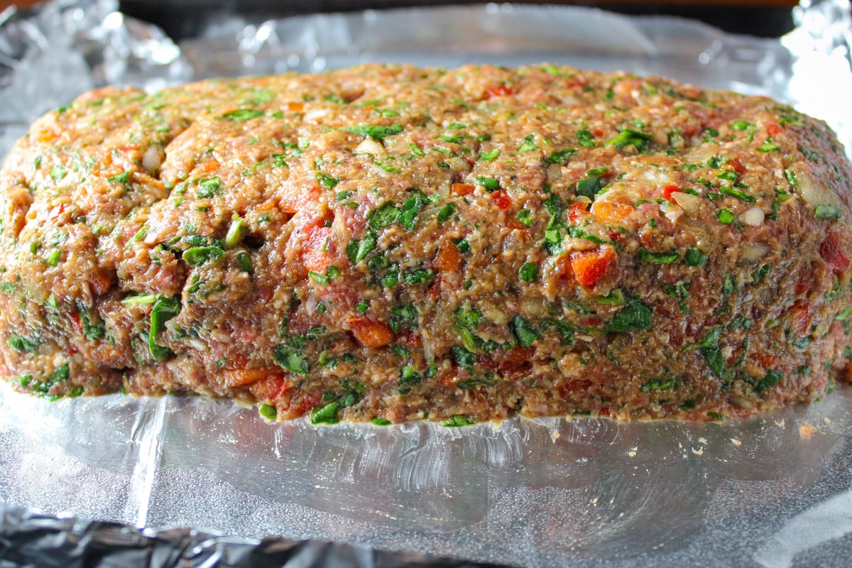 Uncooked formed meatloaf on foil lined pan.