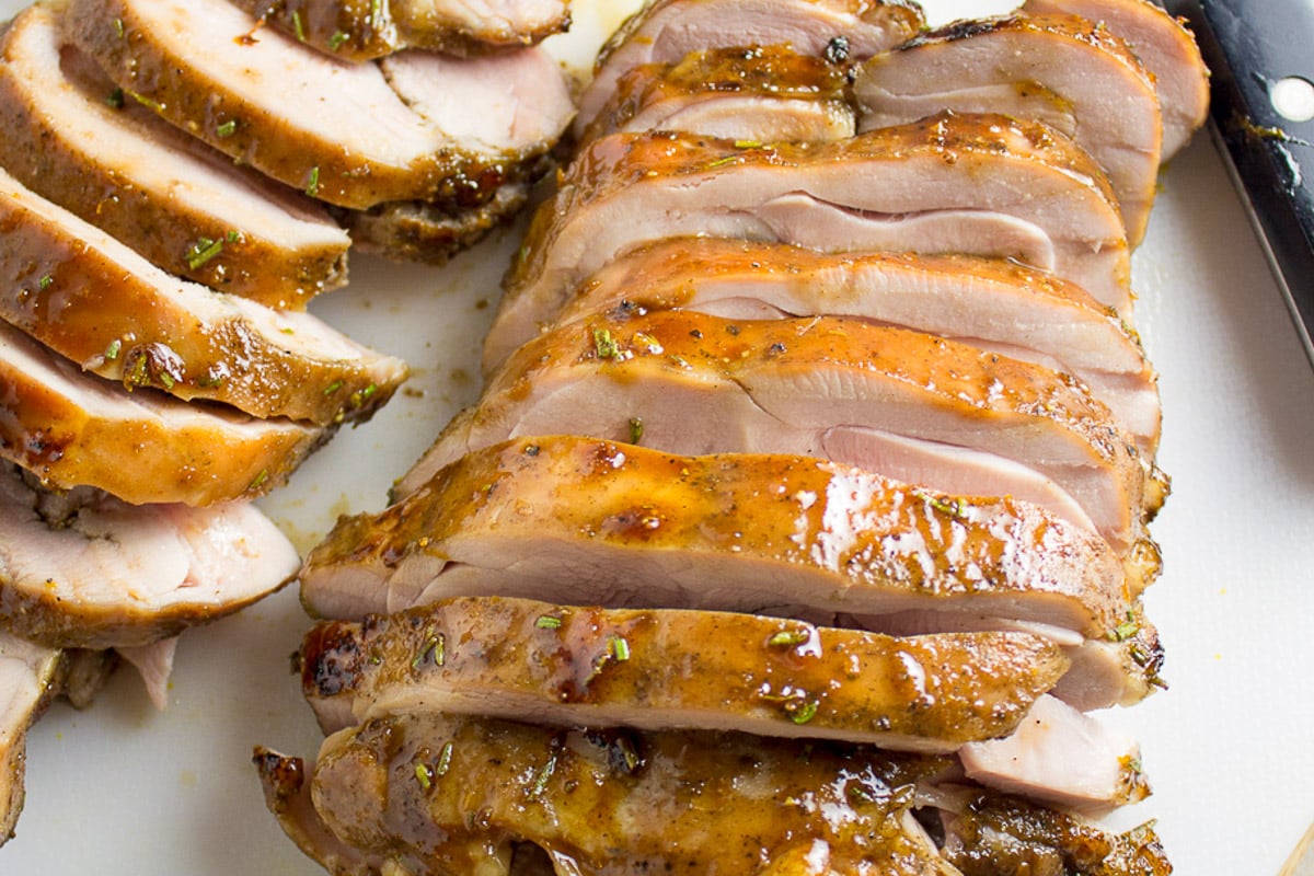 Sliced cooked turkey thighs on cutting board.
