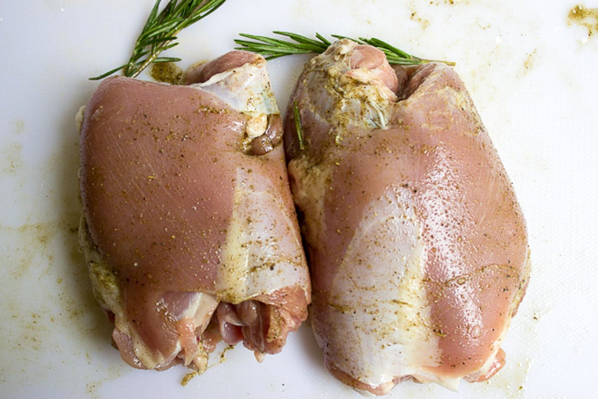 Two seasoned boneless turkey thighs on cutting board.